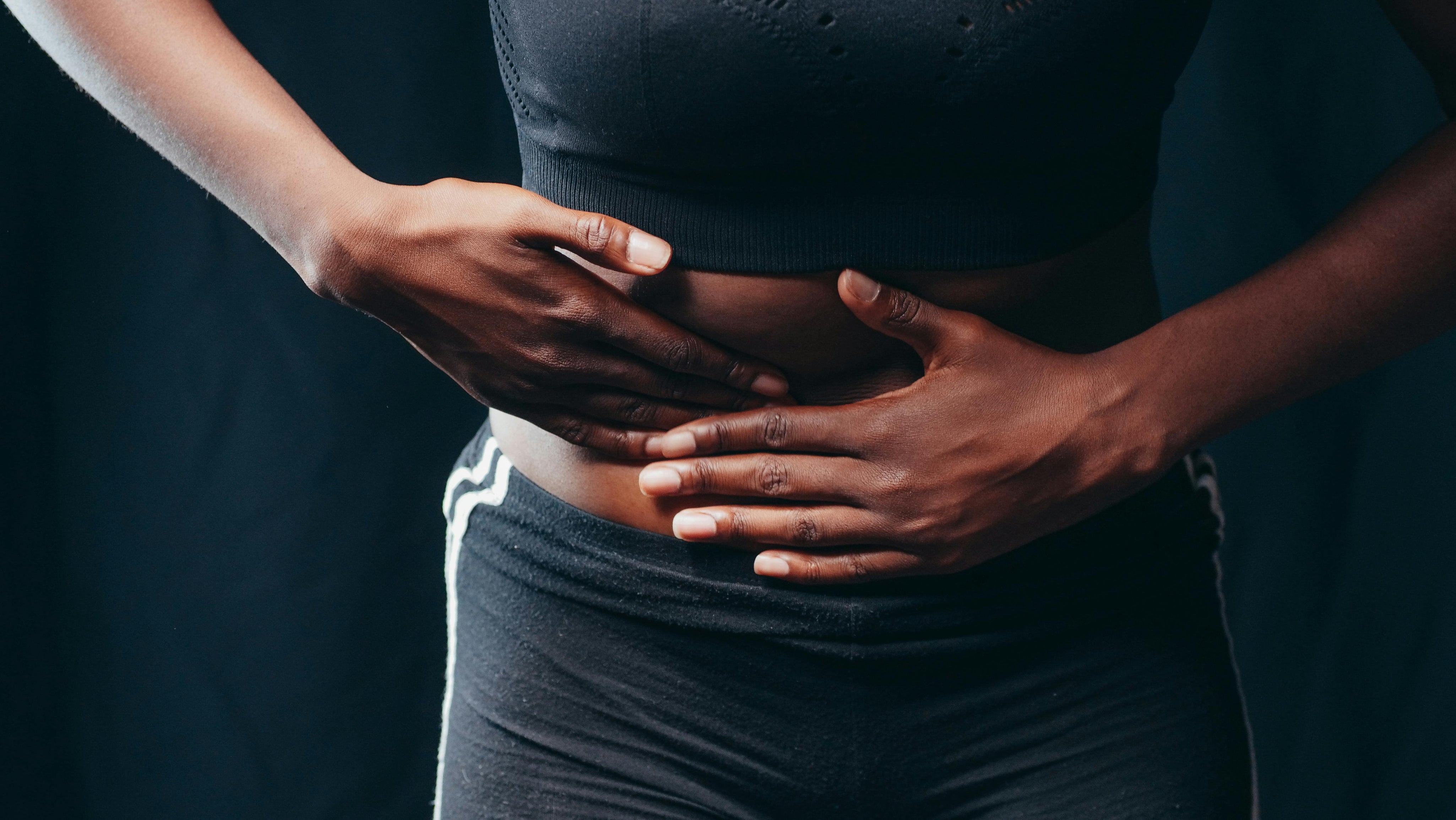 Woman holding abdomen with menstrual cycle calendar, representing period changes.